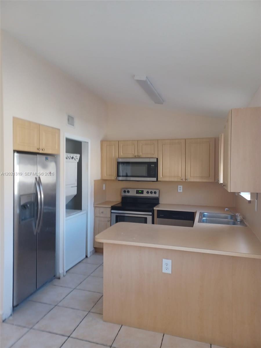 A kitchen features light wood cabinets, stainless steel appliances, and a peninsula counter — 17316 NW 74th Ave # 202, Hialeah FL 33015, HIALEAH, FL