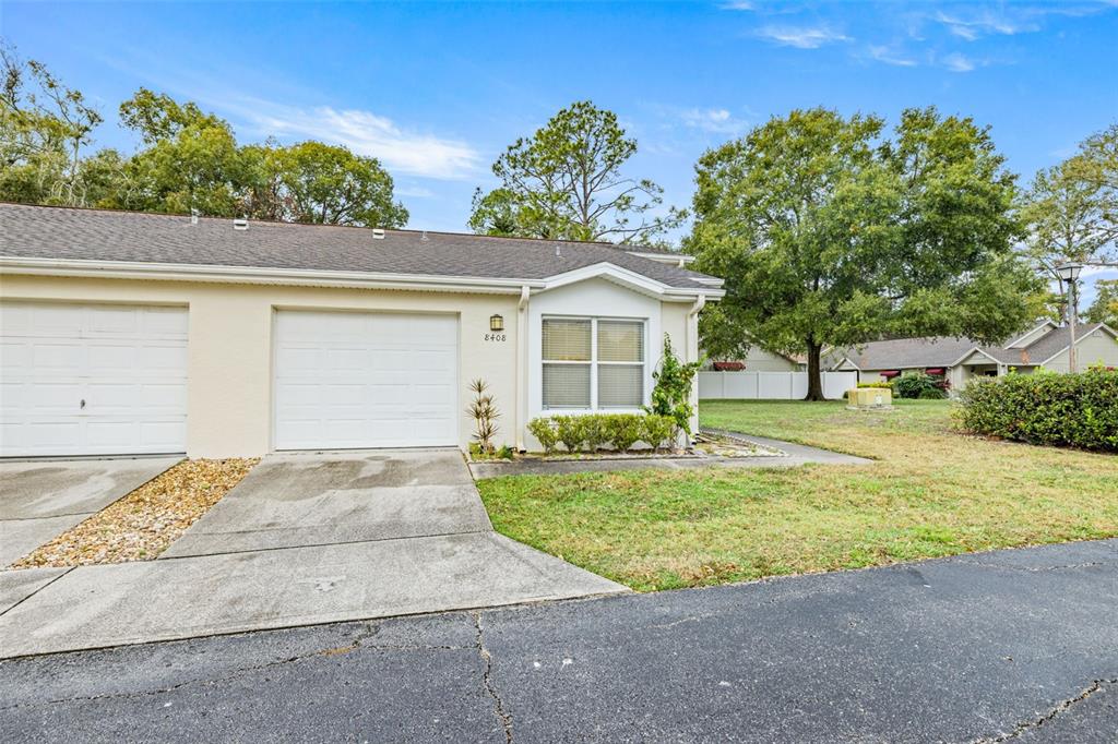 A single-story duplex unit with a white garage door, beige siding, and a concrete driveway — 8408 TERRACE MEADOWS COURT UNIT None, TEMPLE TERRACE, FL