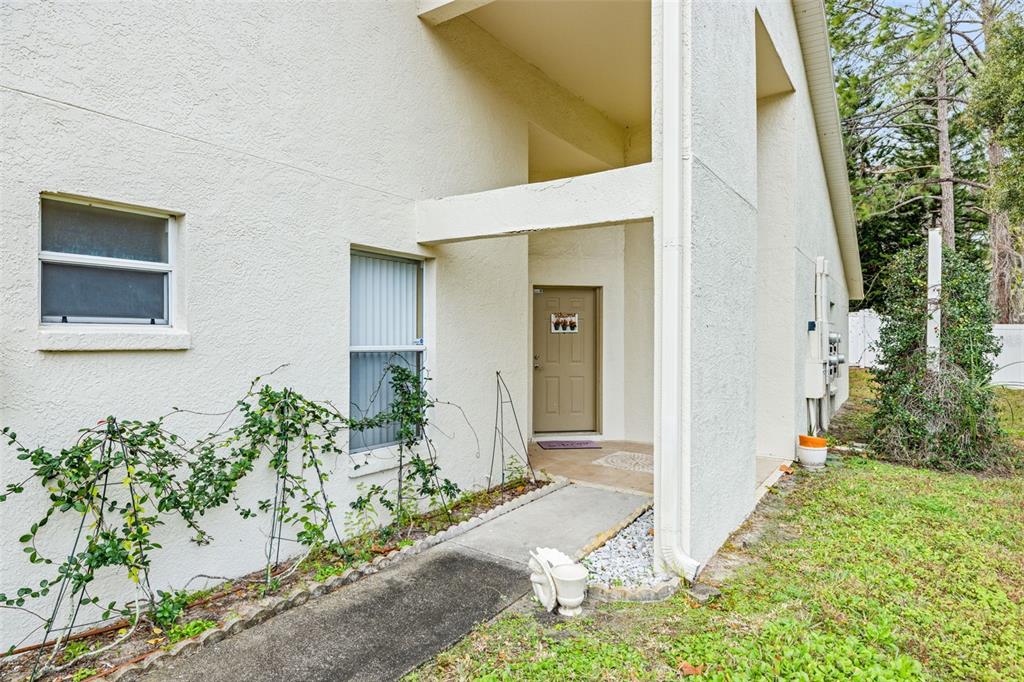 The exterior of a beige stucco building features a covered entryway and a concrete walkway — 8408 TERRACE MEADOWS COURT UNIT None, TEMPLE TERRACE, FL