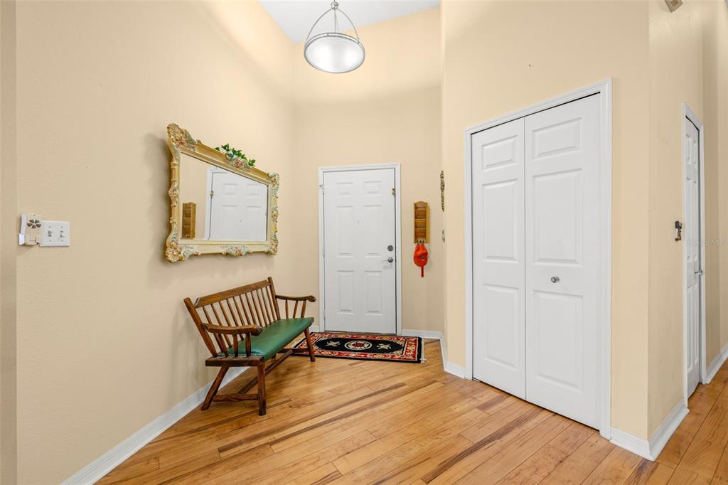 An entryway features hardwood floors, a wooden bench, a mirror, and a white closet door — 8408 TERRACE MEADOWS COURT UNIT None, TEMPLE TERRACE, FL