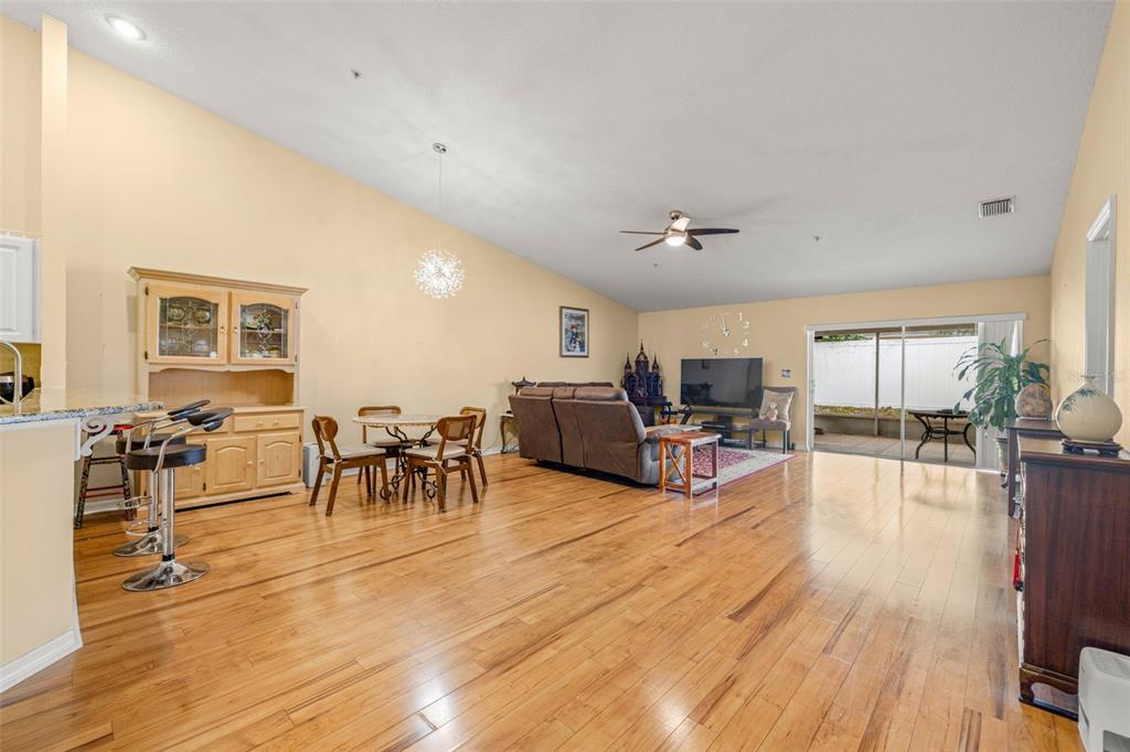 An open-concept living and dining area features hardwood floors, a vaulted ceiling, and sliding doors — 8408 TERRACE MEADOWS COURT UNIT None, TEMPLE TERRACE, FL