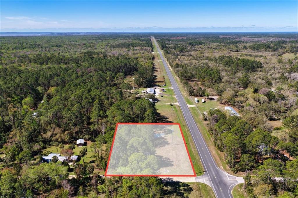 An aerial view shows a rectangular plot of land highlighted in red beside a road — TBD SW STATE ROAD 24, CEDAR KEY, FL