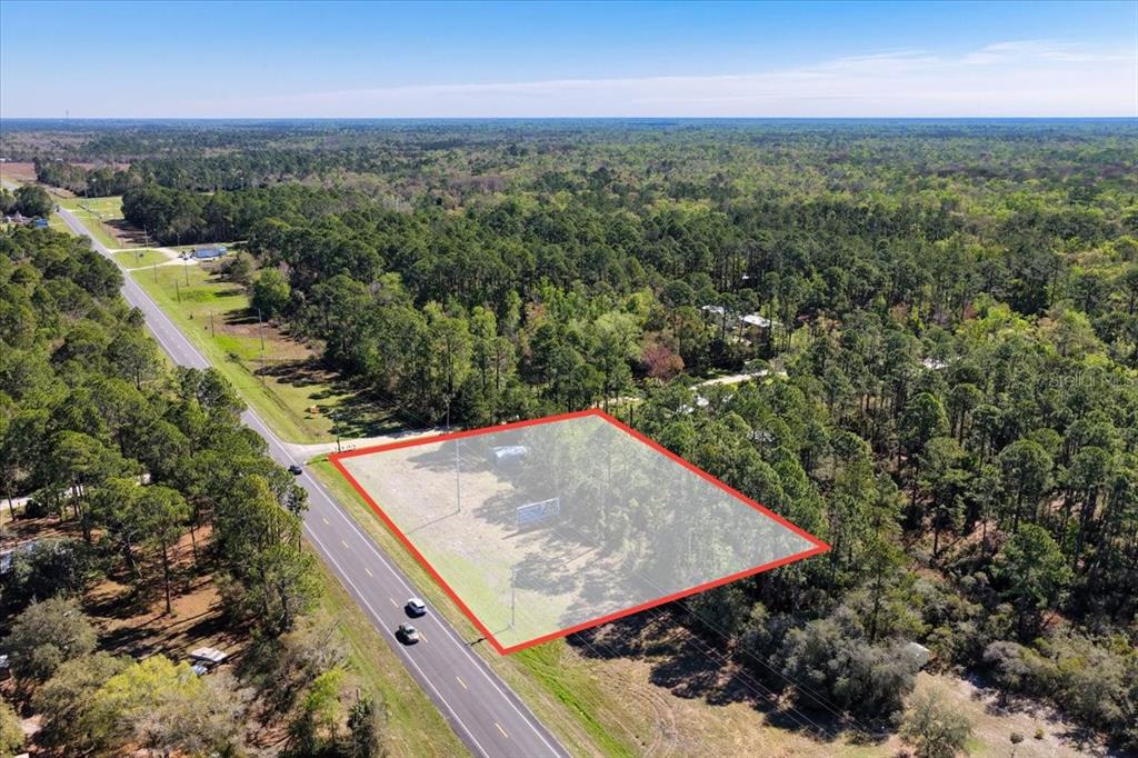 An aerial view shows a rectangular, partially cleared lot bordered by a road and forest — TBD SW STATE ROAD 24, CEDAR KEY, FL