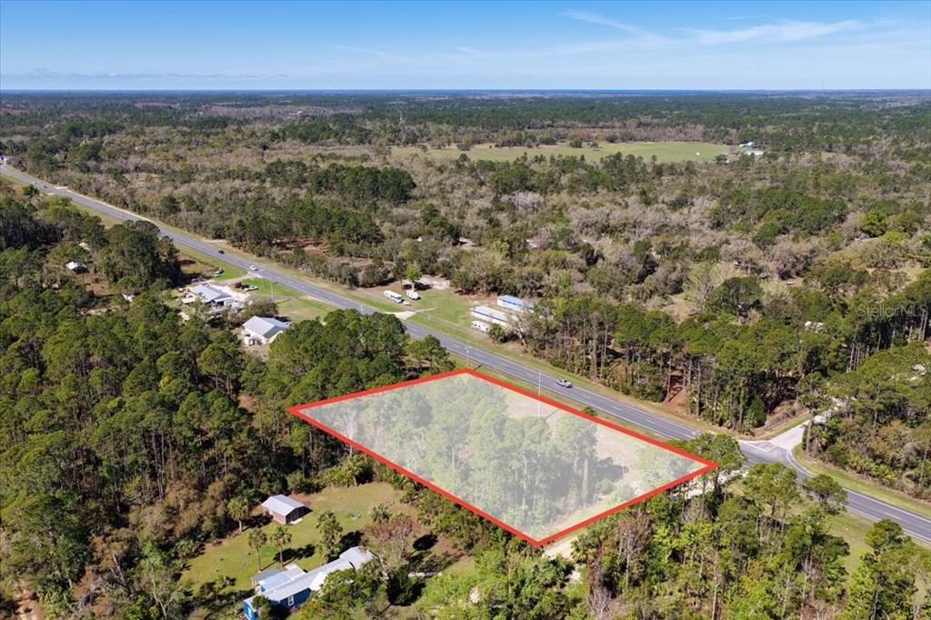 An aerial view shows a rectangular, wooded plot of land bordering a paved road — TBD SW STATE ROAD 24, CEDAR KEY, FL