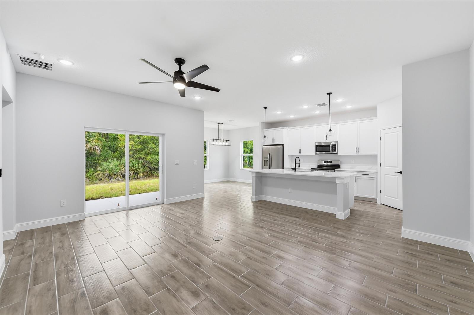 An open-concept kitchen and living area features white cabinets, a center island, and tile flooring — 7825 96th Avenue, Vero Beach FL 32967, VERO BEACH, FL