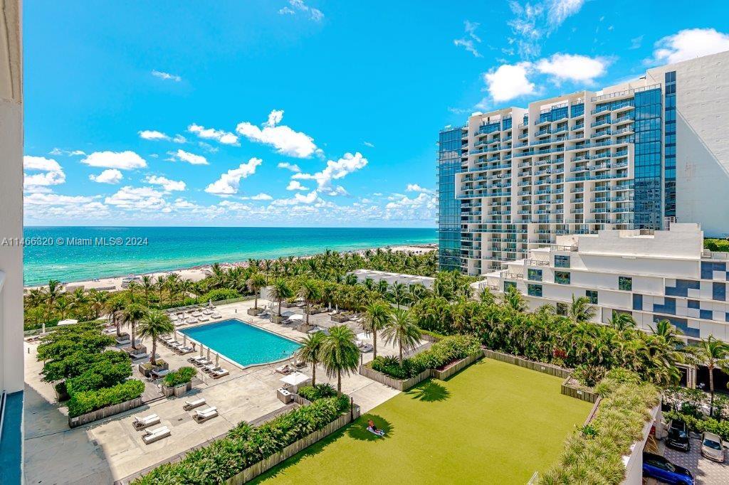 An elevated view shows a swimming pool, a grassy lawn, and a high-rise building by the ocean — 2301 Collins Ave # 803, Miami Beach FL 33139, MIAMI BEACH, FL