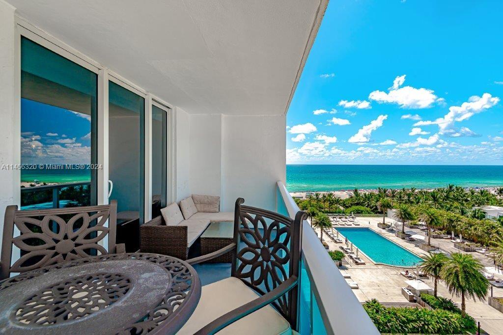 A balcony features outdoor furniture overlooking a swimming pool and the ocean — 2301 Collins Ave # 803, Miami Beach FL 33139, MIAMI BEACH, FL