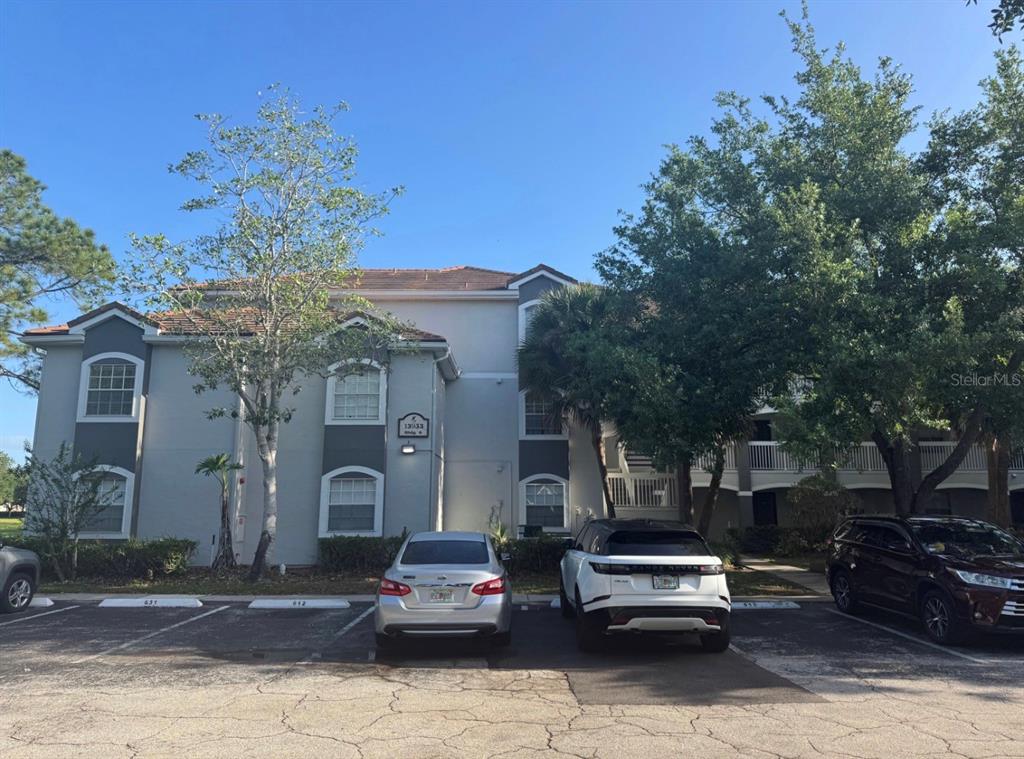 A three-story apartment building exterior with a parking lot in the foreground — 13953 FAIRWAY ISLAND DRIVE UNIT 633, ORLANDO, FL