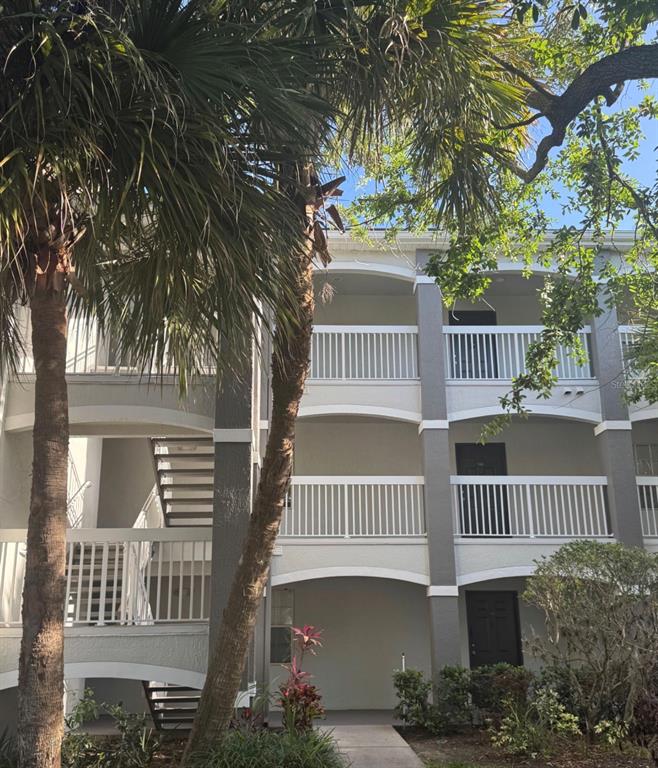 A three-story apartment building exterior features white railings, gray pillars, and an outdoor staircase — 13953 FAIRWAY ISLAND DRIVE UNIT 633, ORLANDO, FL