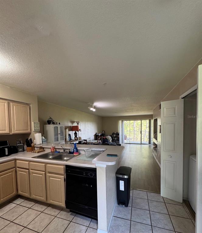 A kitchen with light wood cabinets and a black dishwasher overlooks an open living area — 13953 FAIRWAY ISLAND DRIVE UNIT 633, ORLANDO, FL