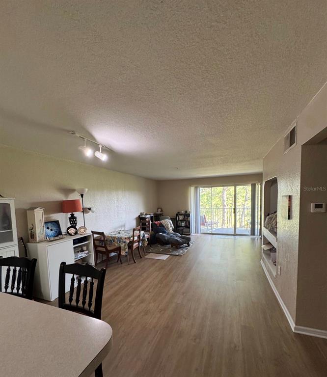 A living and dining area features light wood-look flooring, a sliding glass door, and track lighting — 13953 FAIRWAY ISLAND DRIVE UNIT 633, ORLANDO, FL
