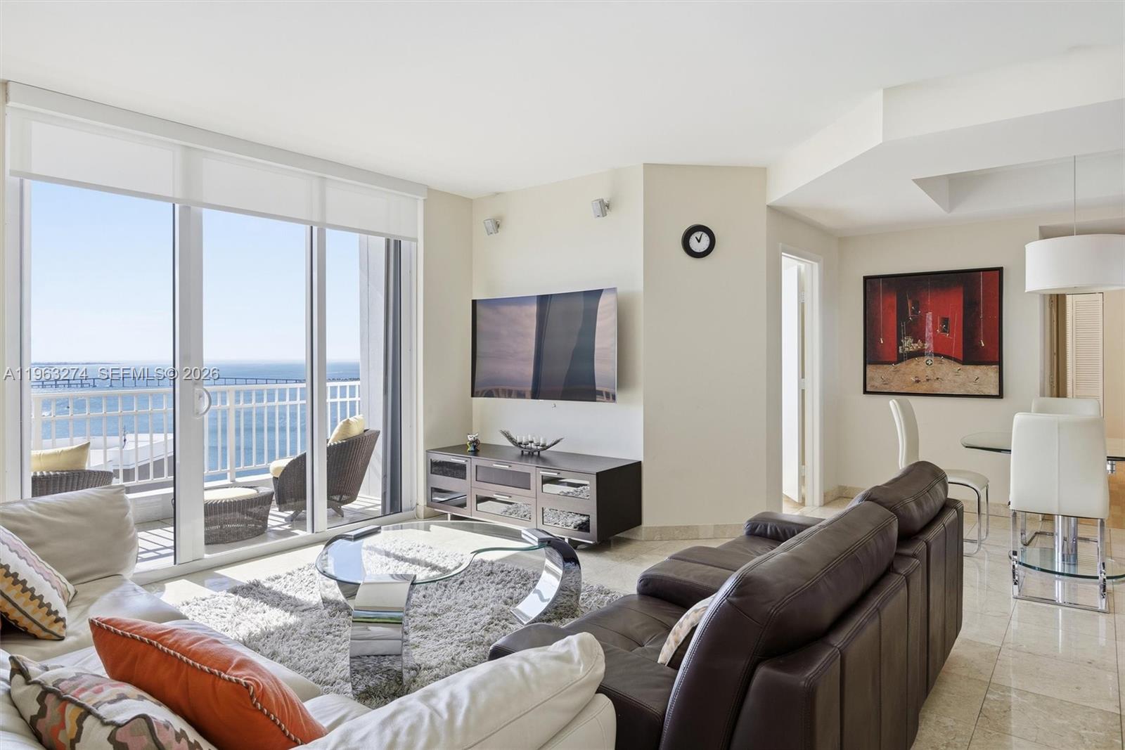 A living room features a dark leather sofa, glass coffee table, and ocean-view balcony access — 801 Brickell Key Blvd # 3209, Miami FL 33131, MIAMI, FL