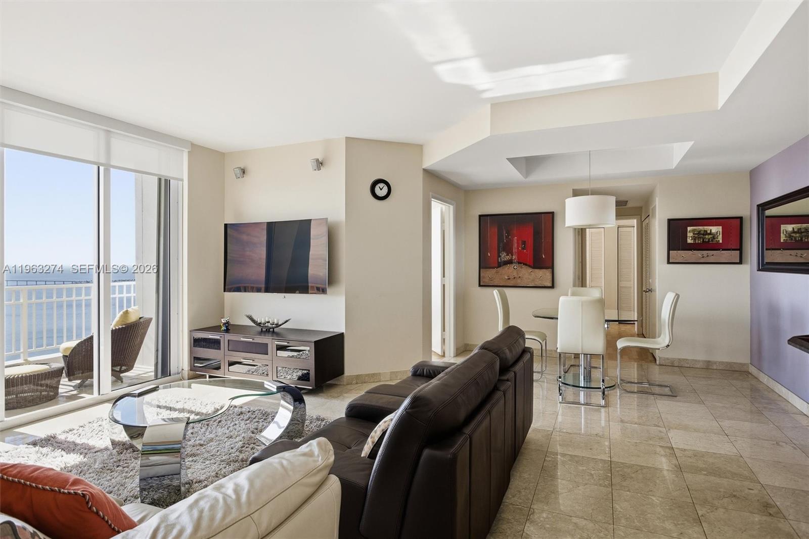 A living and dining area features tile floors, a dark leather sofa, and balcony views — 801 Brickell Key Blvd # 3209, Miami FL 33131, MIAMI, FL