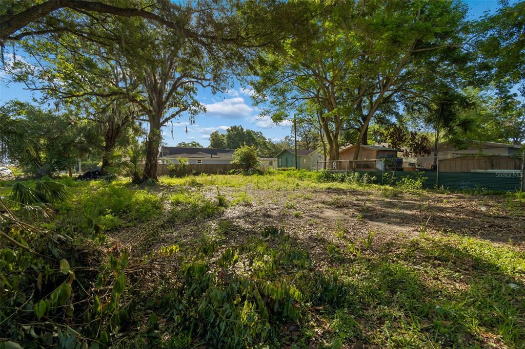 A vacant, grassy lot with several large trees and a fence in the background — 1401 DRANE STREET SE, PLANT CITY, FL