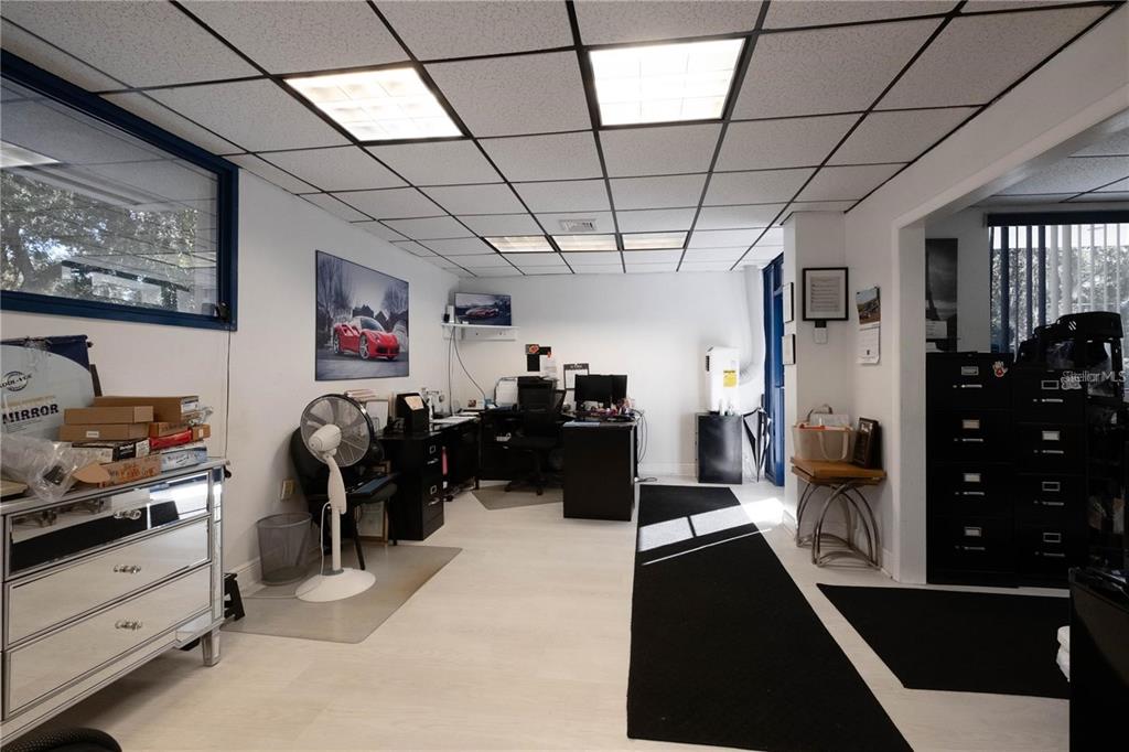 An office space features a drop ceiling, white walls, light flooring, and a black desk — 1820 NE 2ND STREET, GAINESVILLE, FL