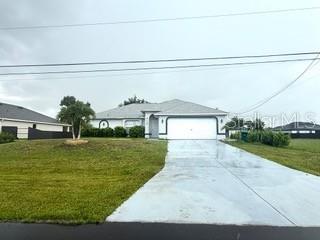 A single-story house with a white garage door and a concrete driveway under a cloudy sky — 313 NW 16TH PLACE, CAPE CORAL, FL