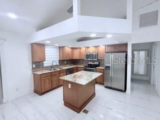 A kitchen features wood cabinets, granite countertops, a center island, and stainless steel appliances — 313 NW 16TH PLACE, CAPE CORAL, FL
