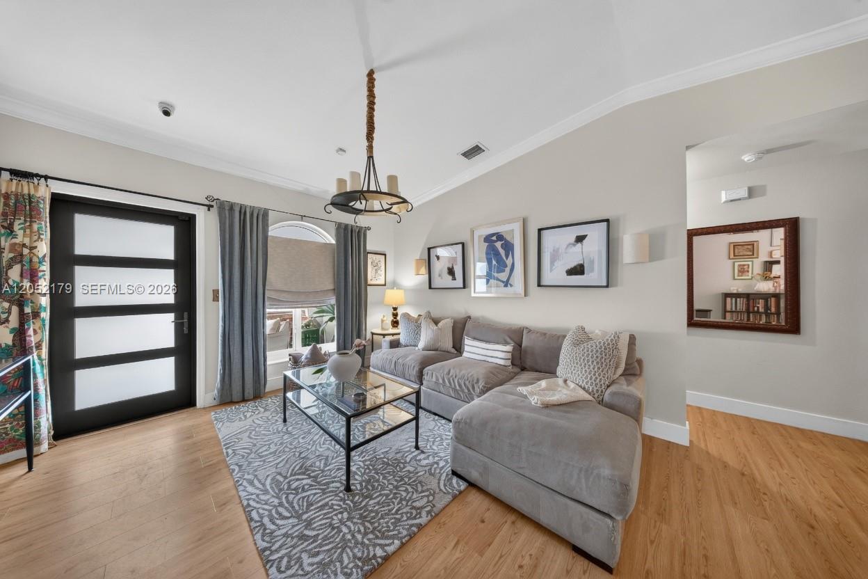 A living room features a gray sectional sofa, a glass coffee table, and a chandelier — HIALEAH, FL