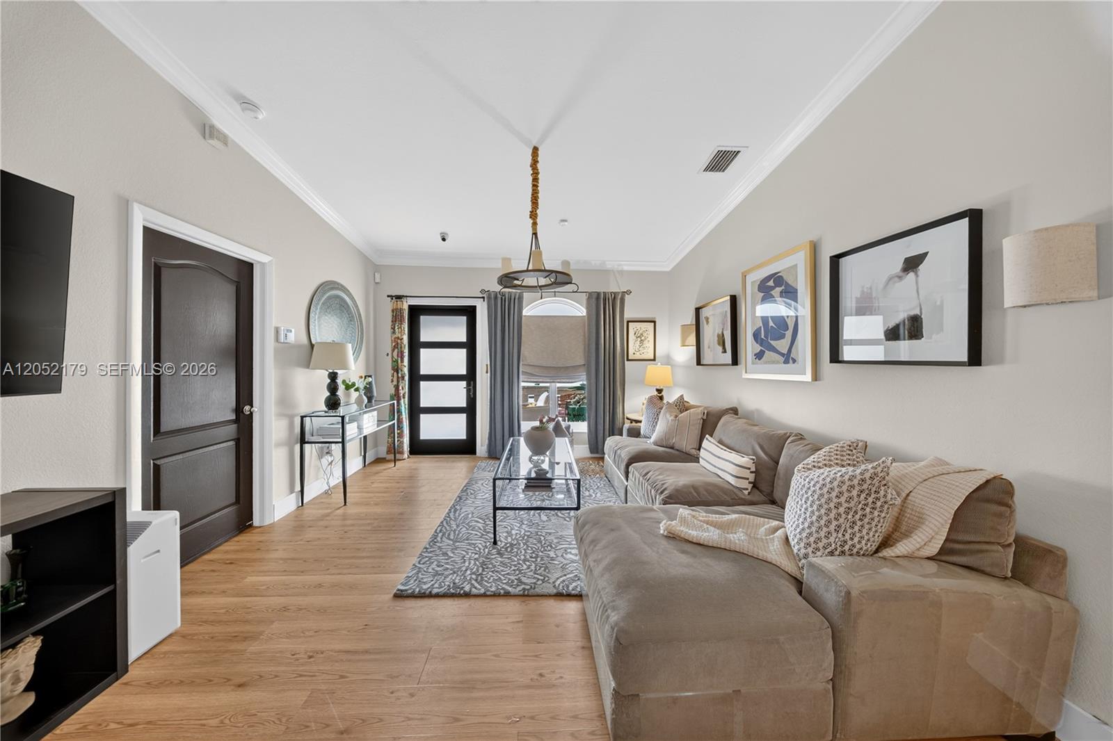 A living room features a sectional sofa, a glass coffee table, and wood flooring — HIALEAH, FL