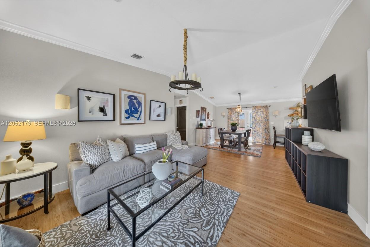 A living room features a gray sectional sofa, a glass coffee table, and wood flooring — HIALEAH, FL