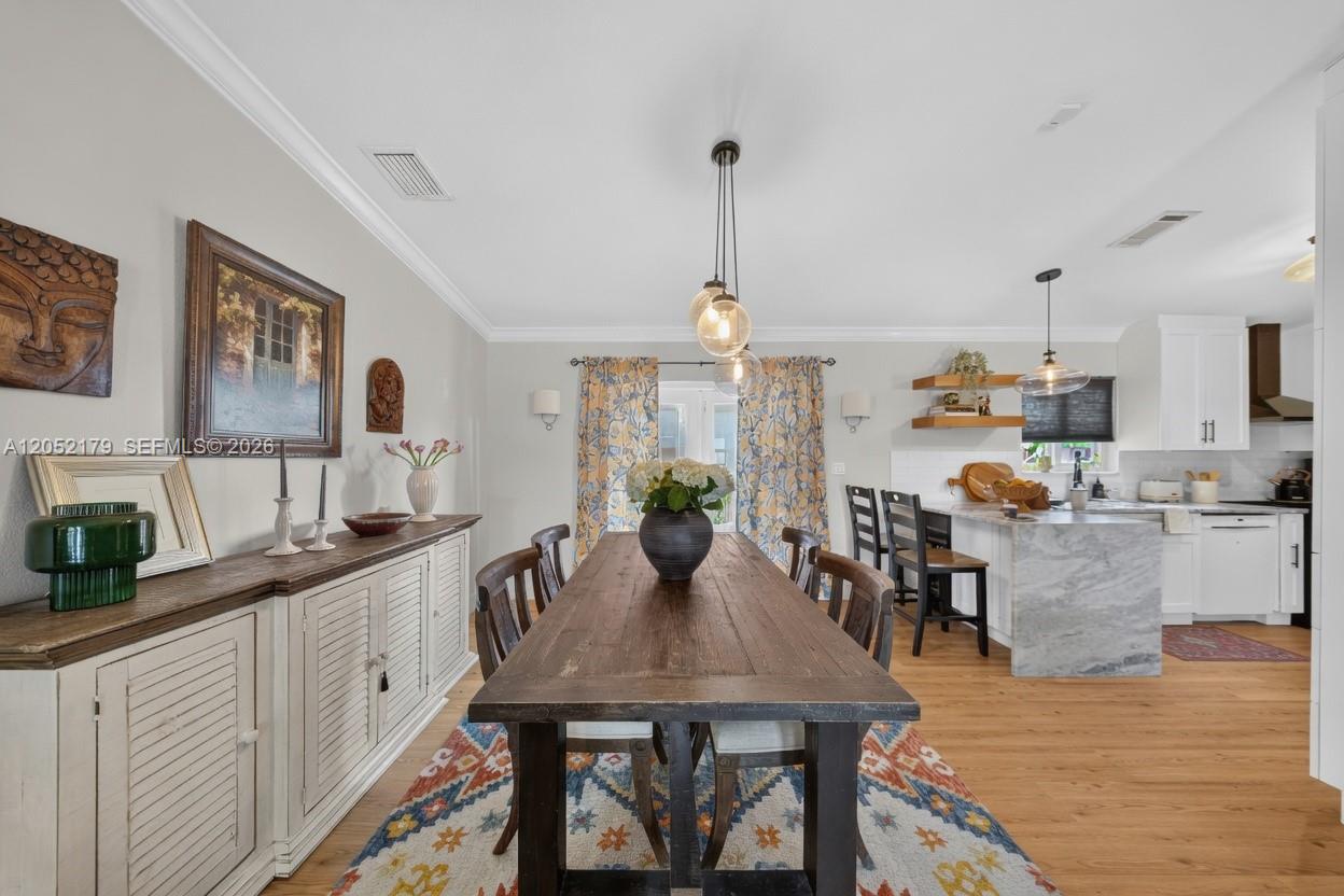 A dining room with a wooden table, white sideboard, and an open kitchen with island — HIALEAH, FL