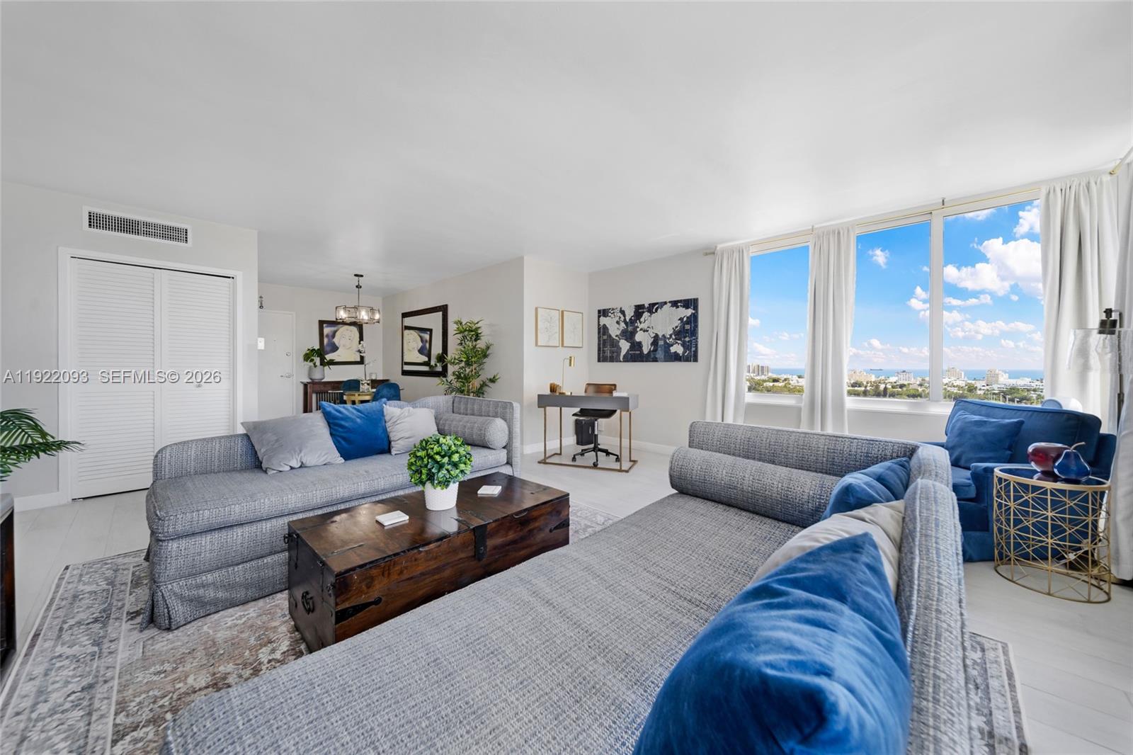 A living room features gray sofas, a wooden trunk coffee table, and large windows — 1200 West Ave # 15, Miami Beach FL 33139, MIAMI BEACH, FL