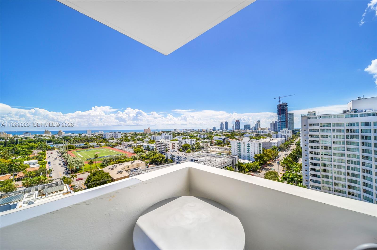 A high-angle view from a white balcony overlooking a city, park, and distant ocean — 1200 West Ave # 15, Miami Beach FL 33139, MIAMI BEACH, FL