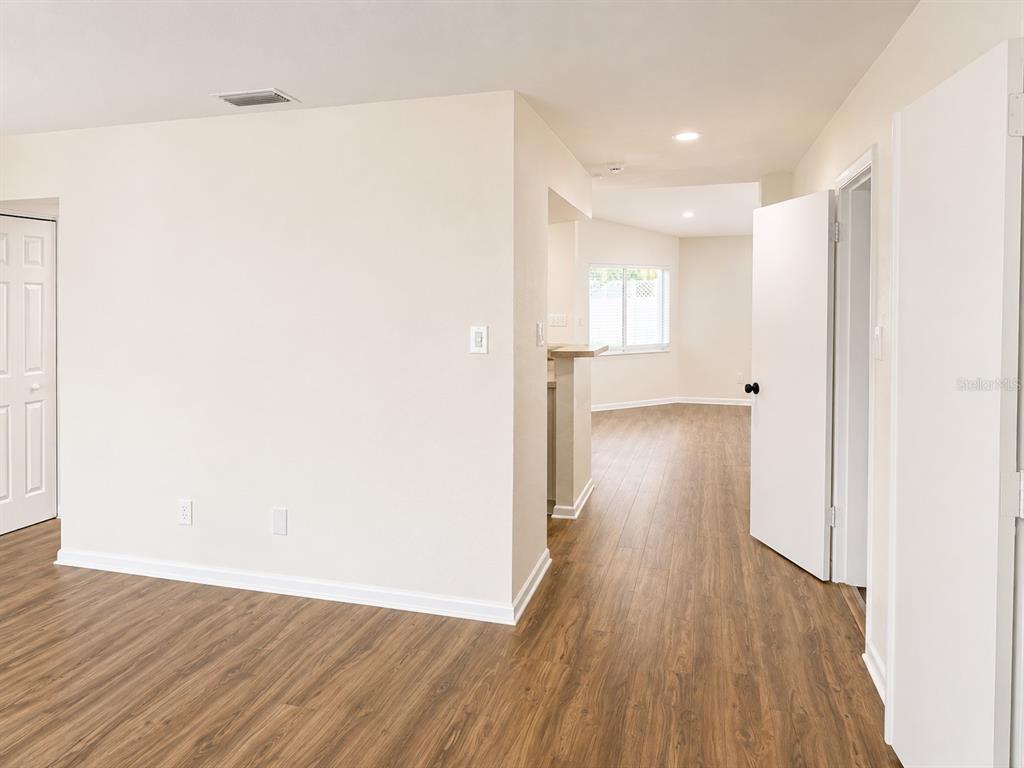 An interior view showing a room with wood-look flooring, white walls, and an open doorway — 1915 W ORIENT STREET, TAMPA, FL