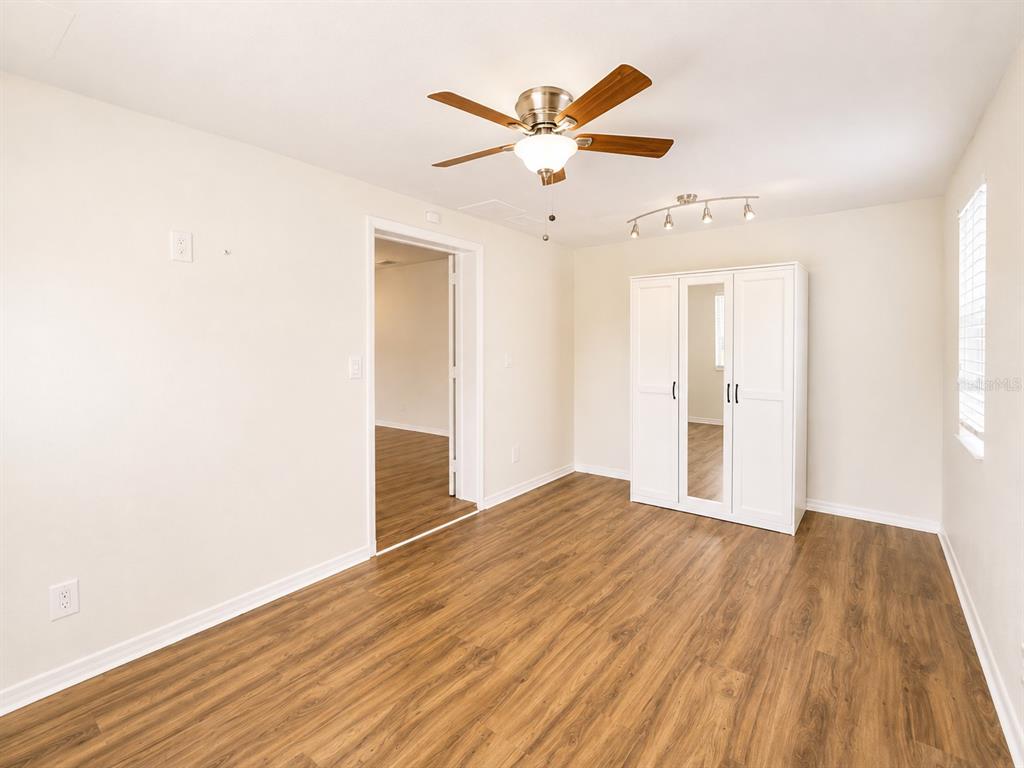 A bedroom with wood-look flooring, a ceiling fan, a white wardrobe, and a doorway — 1915 W ORIENT STREET, TAMPA, FL