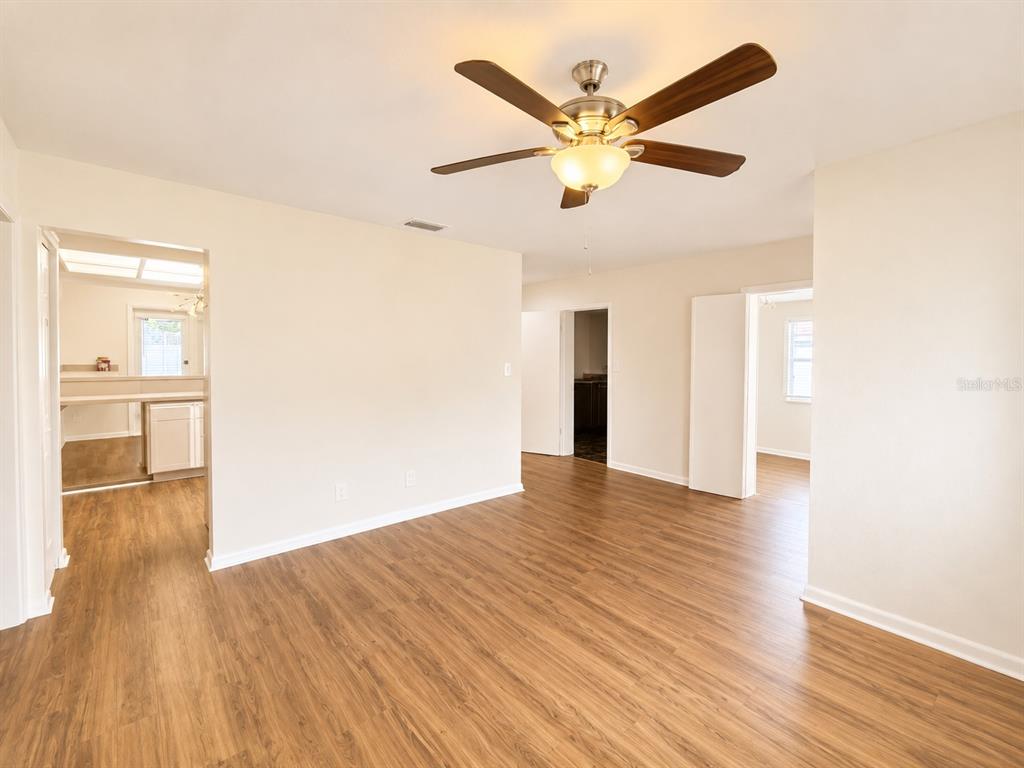An interior view of a room with wood-look flooring, a ceiling fan, and multiple doorways — 1915 W ORIENT STREET, TAMPA, FL