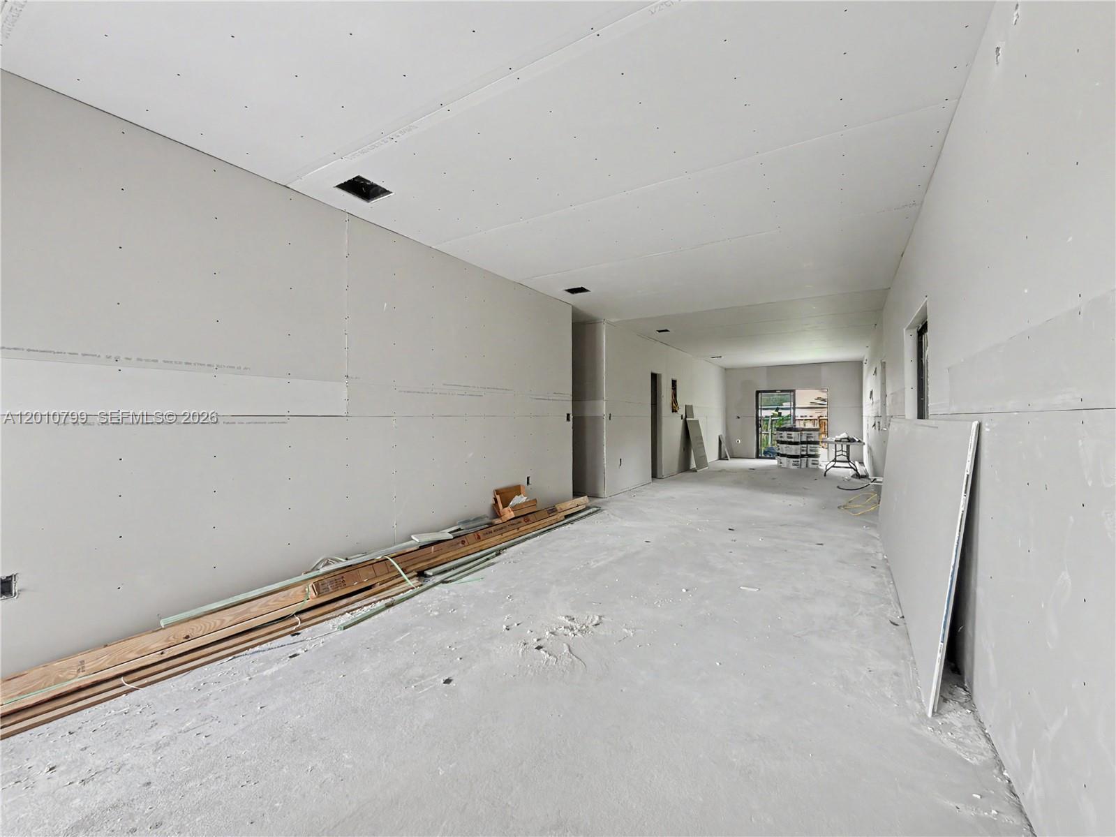 An unfinished room features bare drywall walls and ceiling with concrete flooring and construction materials — 640 SW 10th Ave, Homestead FL 33030, HOMESTEAD, FL