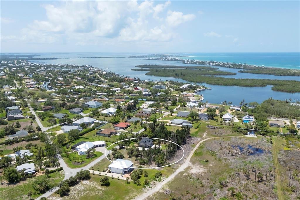 An aerial view shows a house surrounded by trees and a nearby coastal landscape — 55 GREEN DOLPHIN DRIVE N, PLACIDA, FL