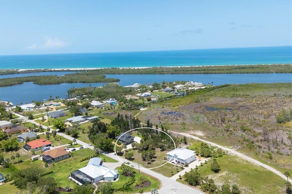 An aerial view shows a residential neighborhood with a circled house near a coastal waterway — 55 GREEN DOLPHIN DRIVE N, PLACIDA, FL