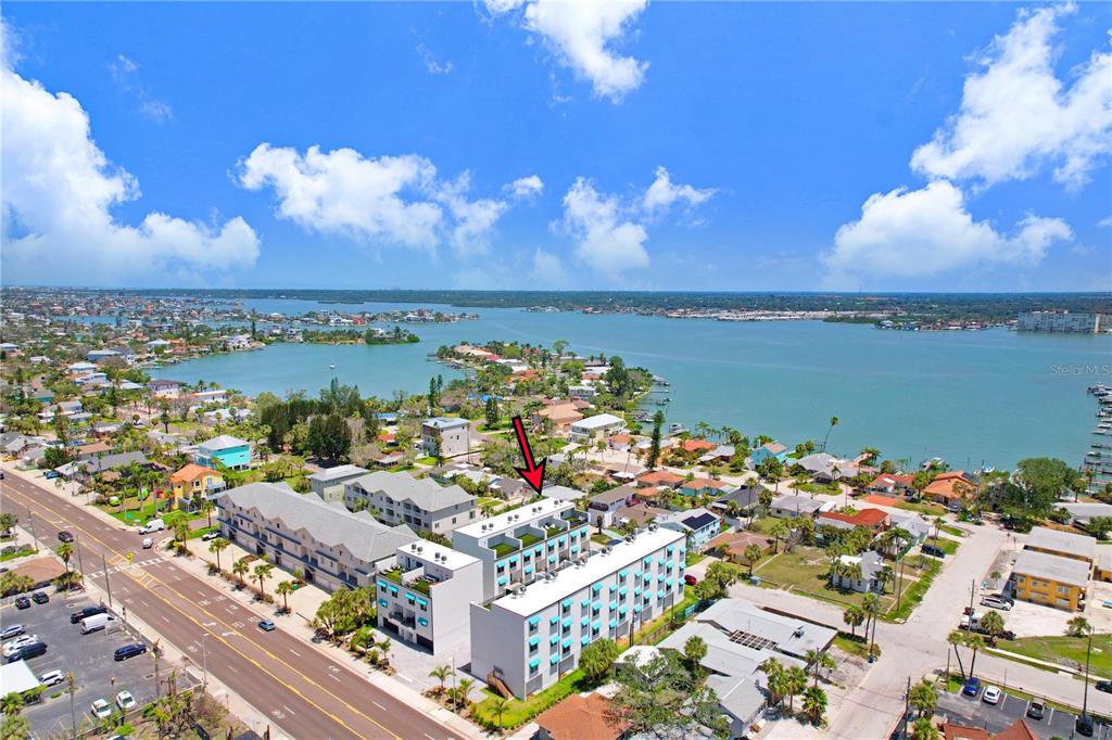 An aerial view shows a multi-story apartment building near a coastal waterway — 15405 GULF BOULEVARD UNIT B4, ST PETERSBURG, FL
