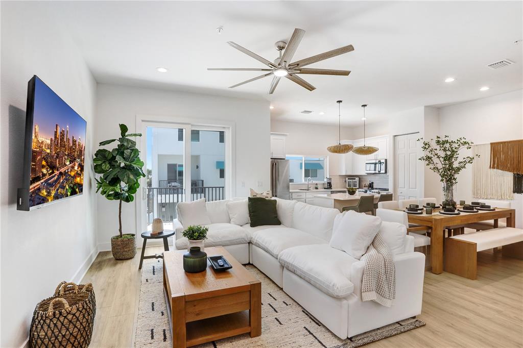 An open-concept living and dining area features a white sectional, wood coffee table, and kitchen — 15405 GULF BOULEVARD UNIT B4, ST PETERSBURG, FL