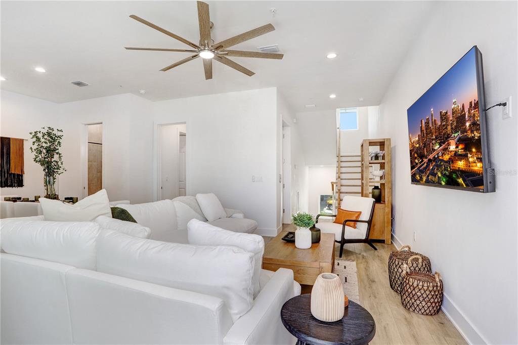 A bright living room features a white sectional sofa, a wooden coffee table, and a wall-mounted television — 15405 GULF BOULEVARD UNIT B4, ST PETERSBURG, FL