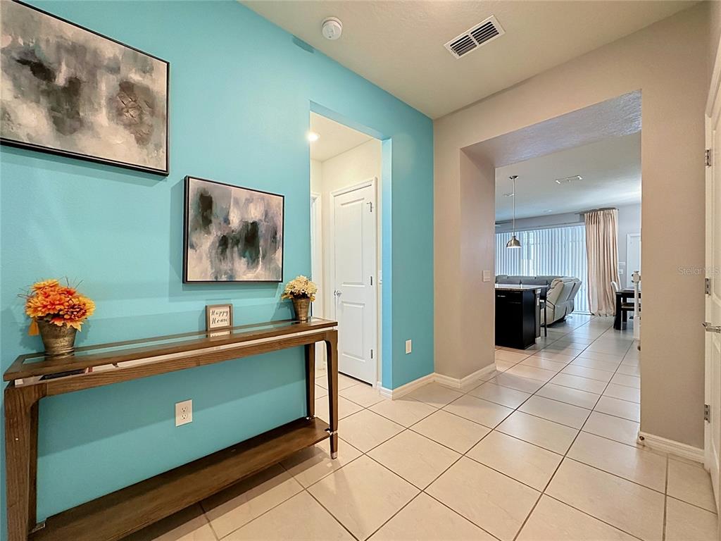 A turquoise entryway features a wooden console table, wall art, and tile flooring — 267 JETTY WAY, DAVENPORT, FL