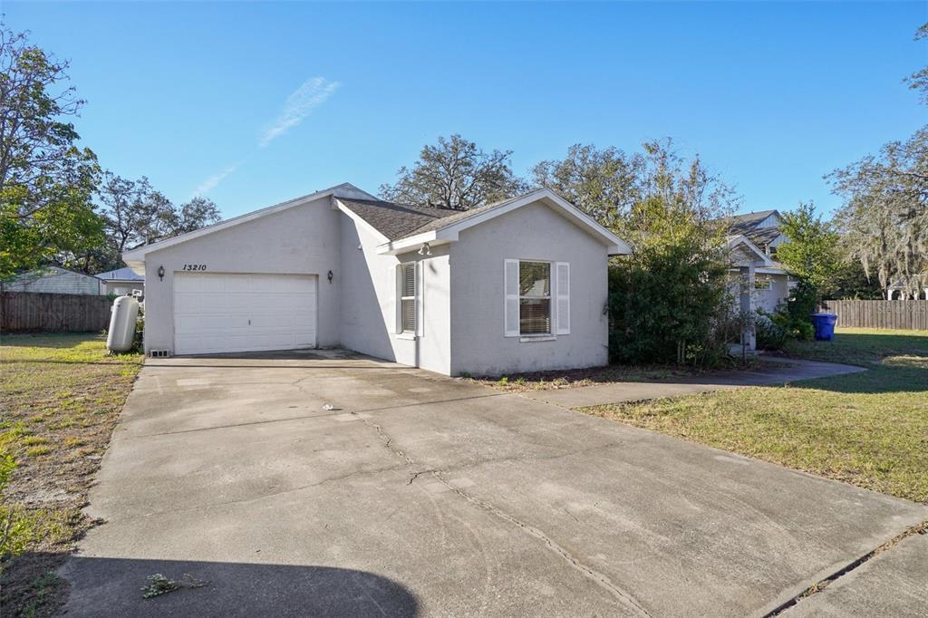 A single-story house with a white garage door and a concrete driveway — 13210 MAPLE STREET, ODESSA, FL
