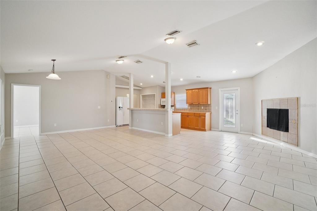 An open-concept living room and kitchen with tile flooring, a fireplace, and wooden cabinets — 13210 MAPLE STREET, ODESSA, FL