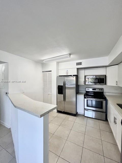 A kitchen features white cabinets, stainless steel appliances, and a breakfast bar with tile flooring — 3690 N 56th Ave # 902, Hollywood FL 33021, HOLLYWOOD, FL