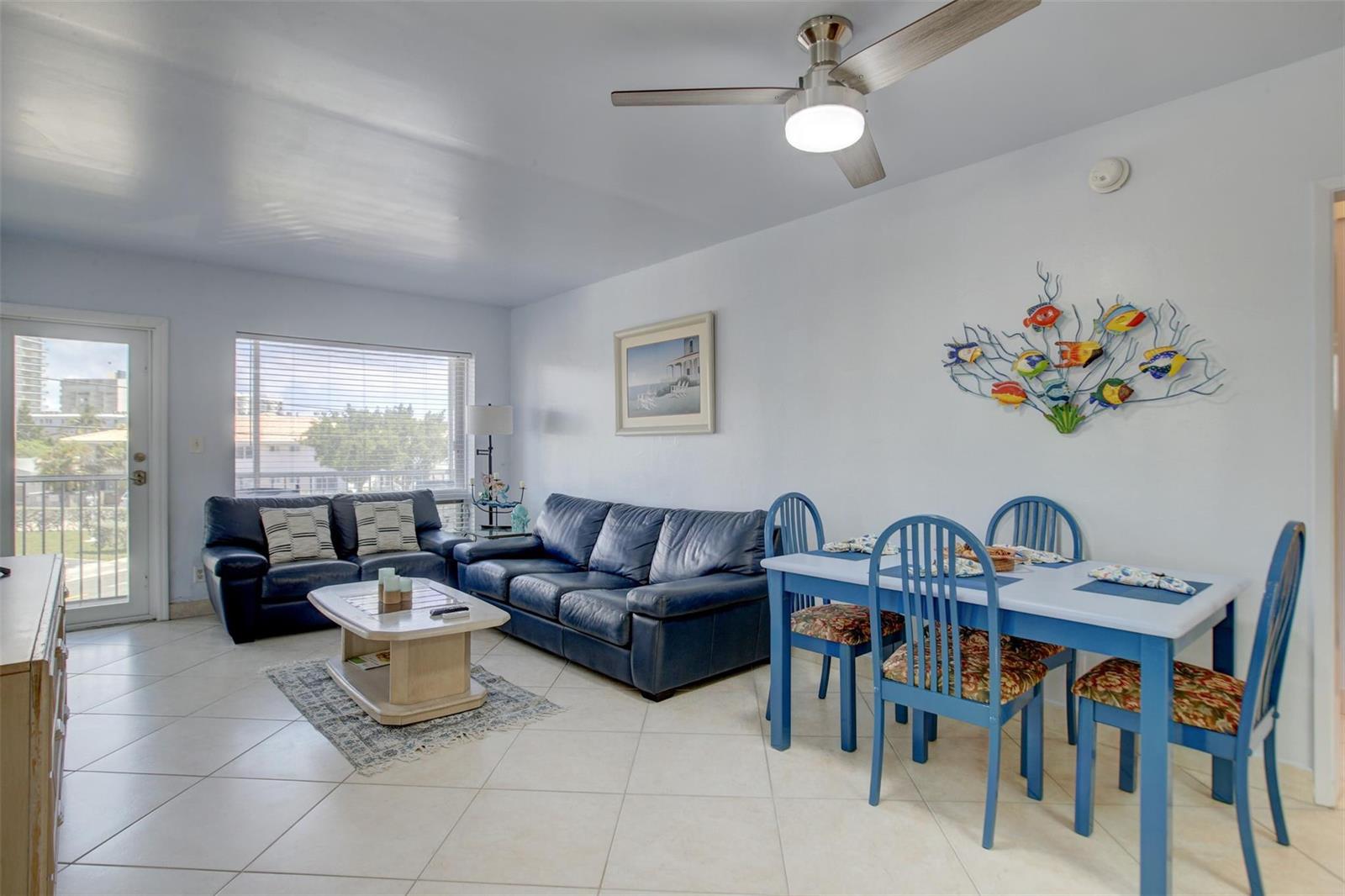A living and dining area features blue leather sofas, a dining set, and tile flooring — 999 N Riverside Drive # 11, Pompano Beach FL 33062, POMPANO BEACH, FL