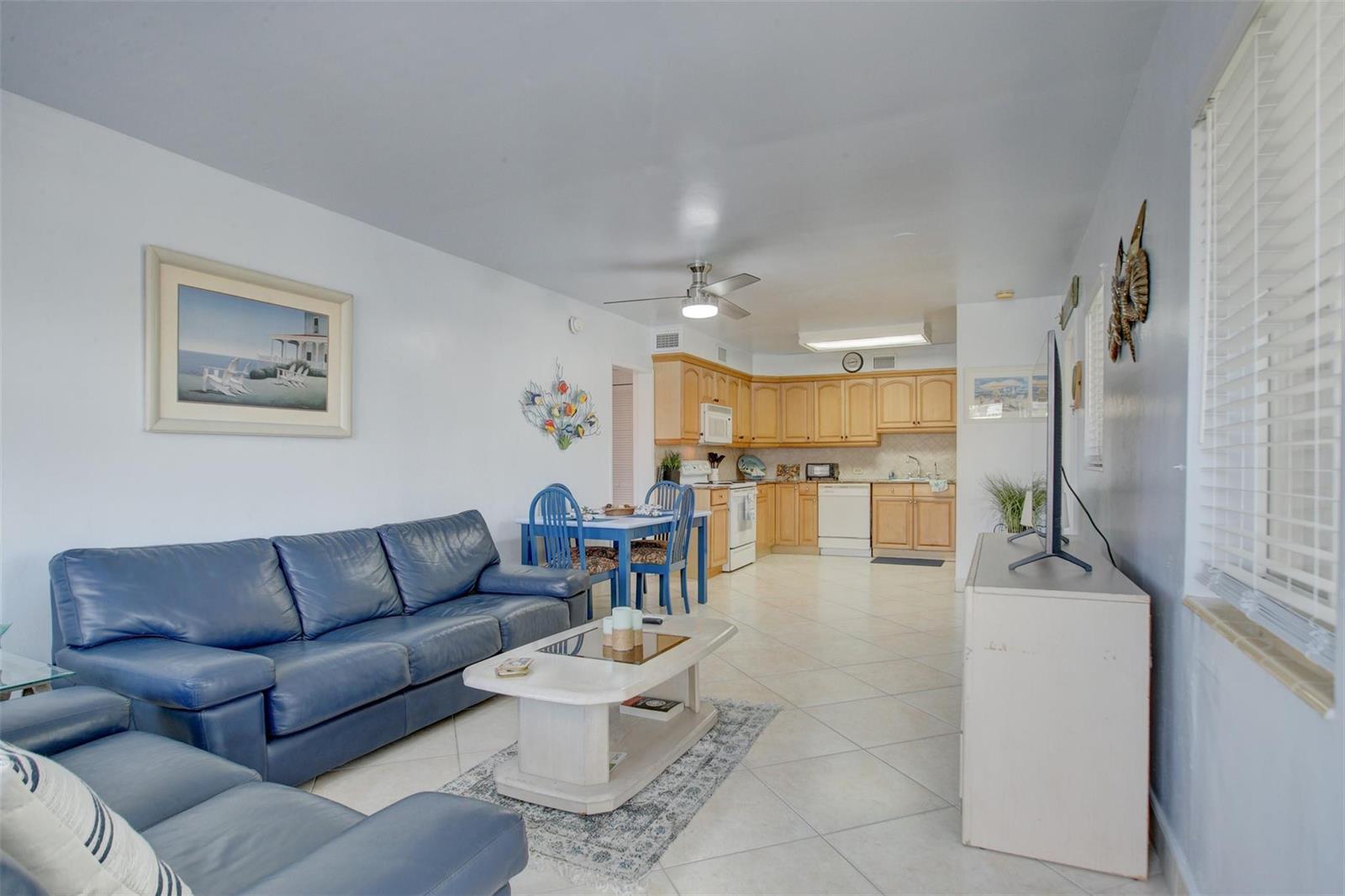 A living room with a blue leather sofa and a kitchen with light wood cabinets — 999 N Riverside Drive # 11, Pompano Beach FL 33062, POMPANO BEACH, FL