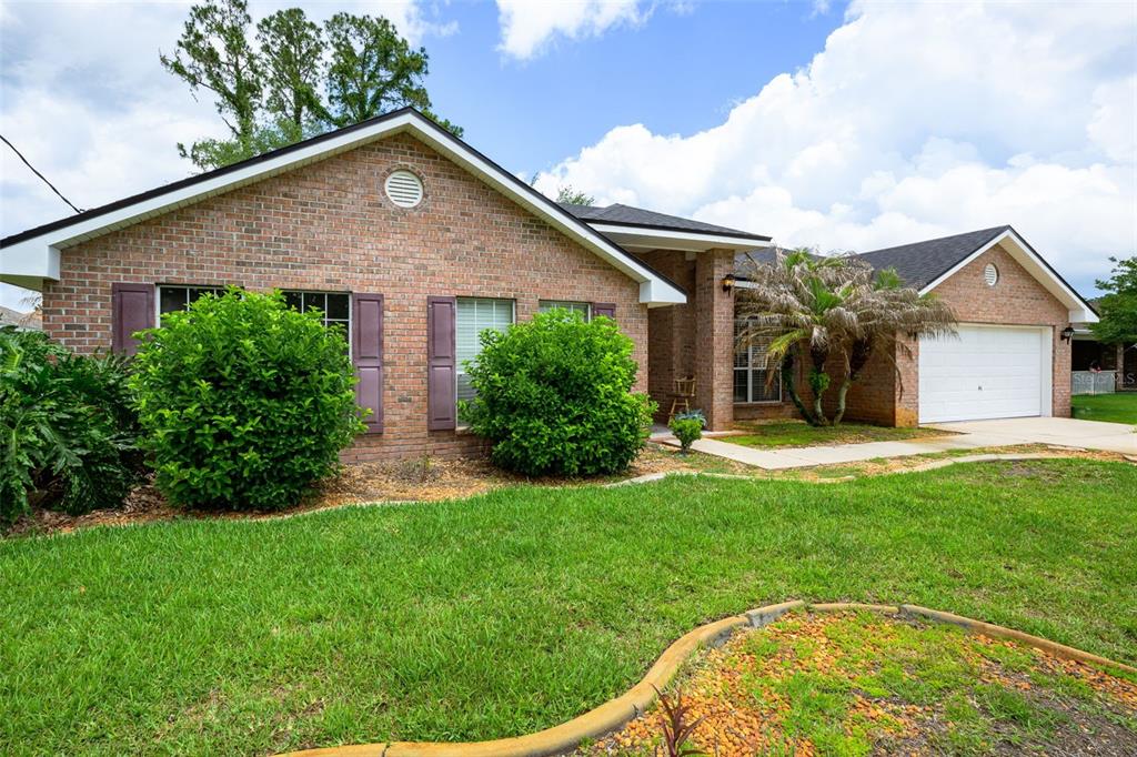 A single-story brick house features a two-car garage, dark shutters, and a landscaped front yard — 11 RIDDLE DRIVE, PALM COAST, FL