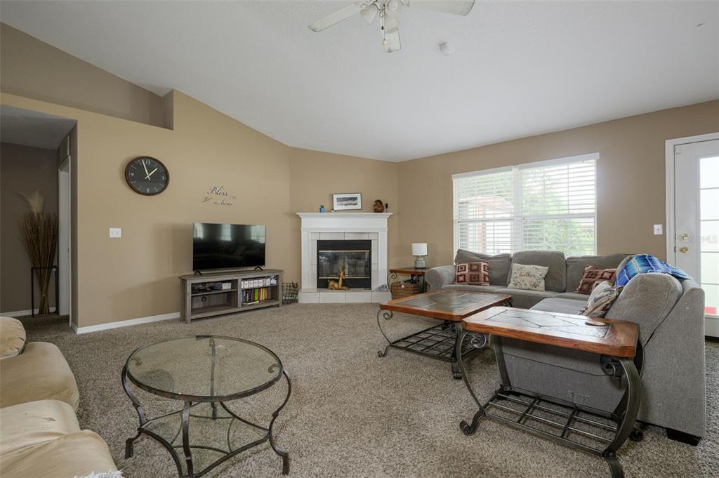A living room features beige walls, carpeted flooring, a fireplace, and a sectional sofa — 11 RIDDLE DRIVE, PALM COAST, FL