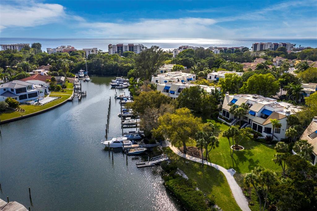 A multi-story residential building with brown garage doors, blue awnings, and a large oak tree — 1906 HARBOURSIDE DRIVE UNIT 304, LONGBOAT KEY, FL