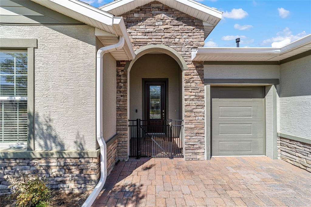 A stone-accented home exterior features a gated entryway, a single garage, and paver driveway — 3584 NW 56TH AVENUE, OCALA, FL