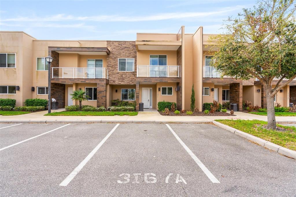 A row of modern two-story townhouses with balconies and stone accents faces a parking lot — 3167A BRASILIA AVENUE, KISSIMMEE, FL