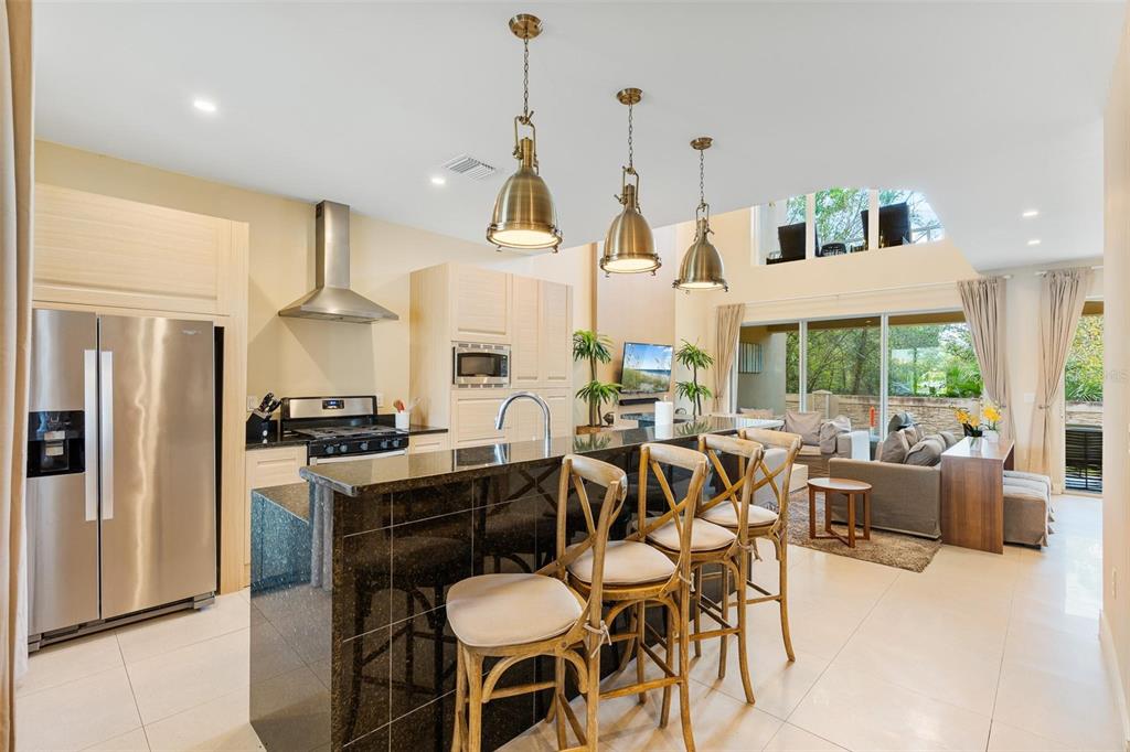 A kitchen with a black granite island and bar stools opens into a living area — 3167A BRASILIA AVENUE, KISSIMMEE, FL