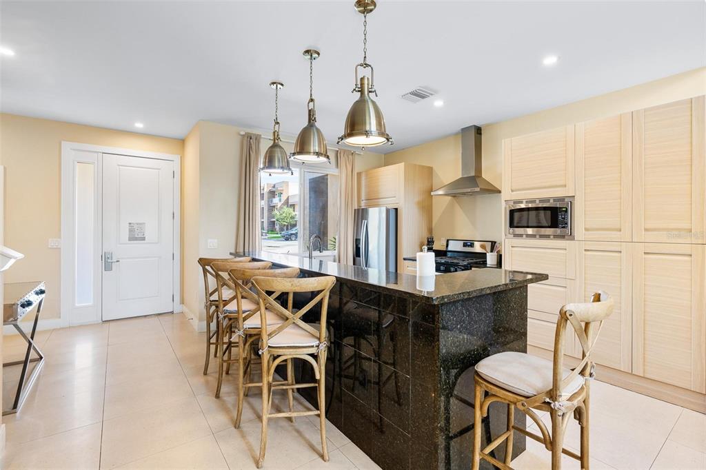 A kitchen features a dark granite island, light wood cabinetry, and three pendant lights — 3167A BRASILIA AVENUE, KISSIMMEE, FL