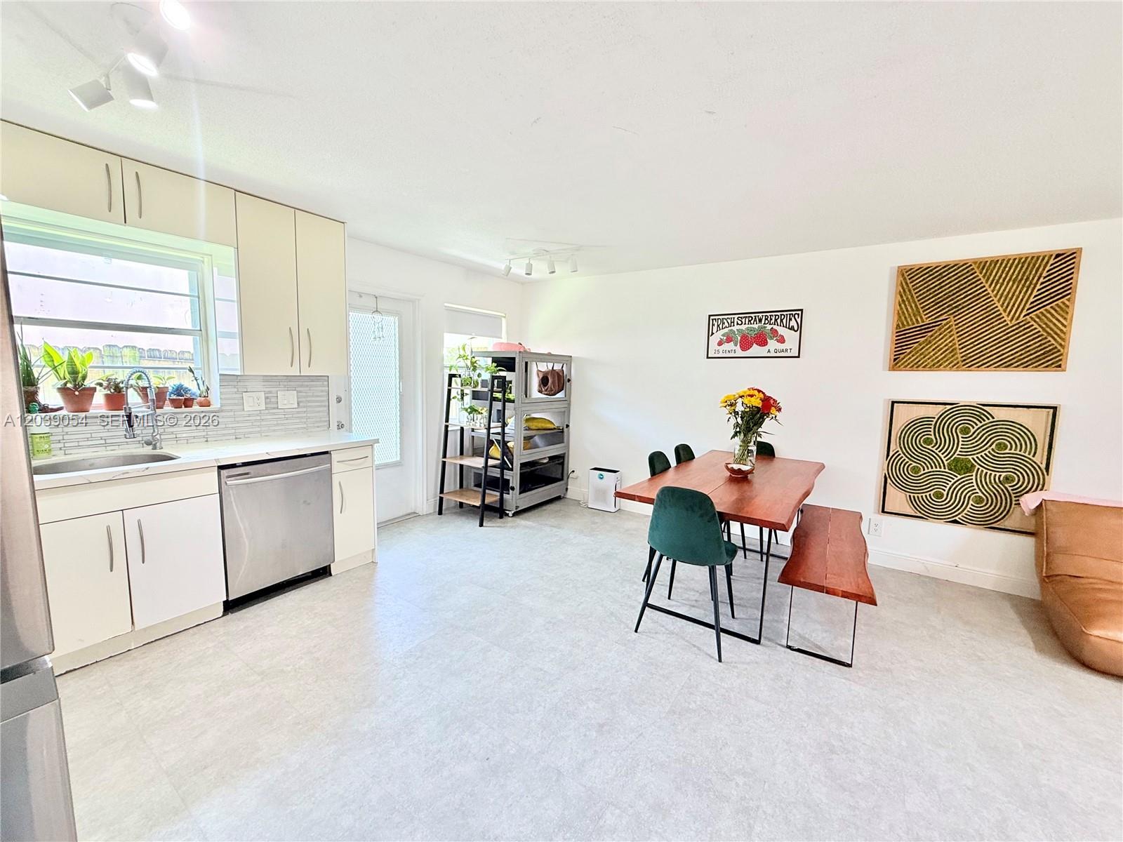 A kitchen and dining area features white cabinets, stainless steel appliances, and a wooden table — 1722 Mayo St # 105, Hollywood FL 33020, HOLLYWOOD, FL